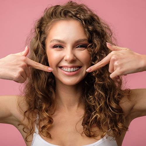 woman smiling while pointing to braces