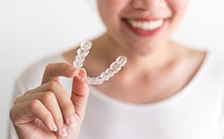 woman smiling and holding clear aligner 