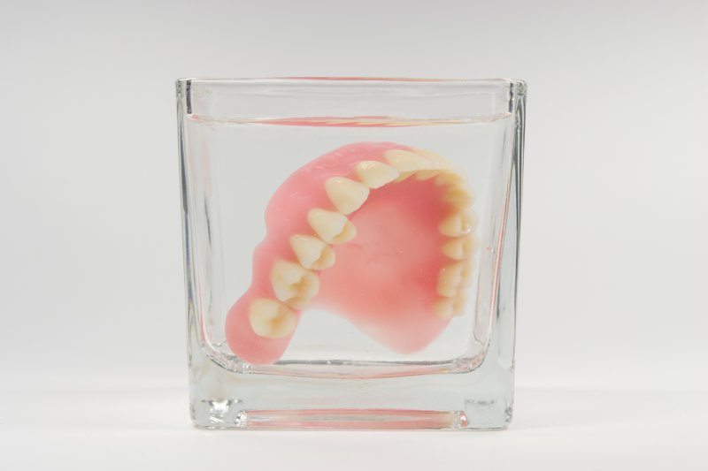 upper denture soaking in glass of water