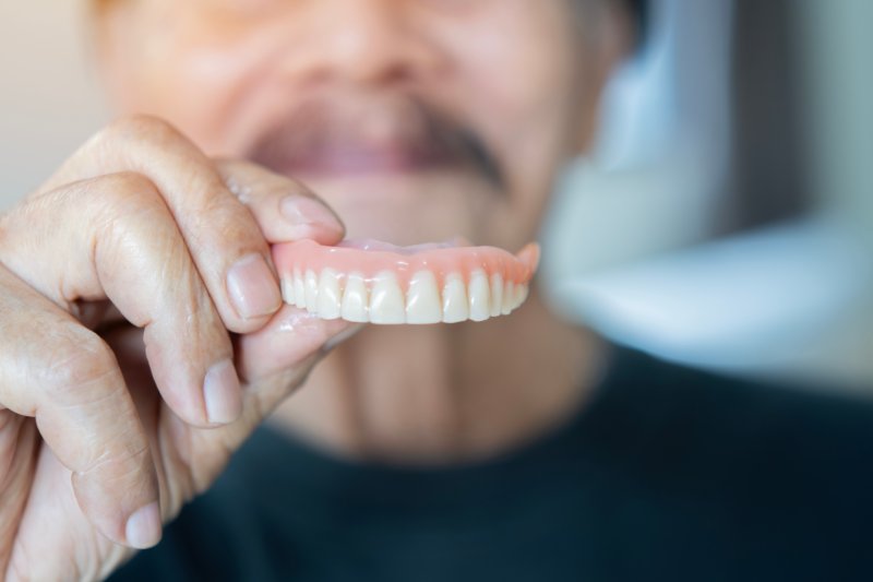 Older patient holding their dentures